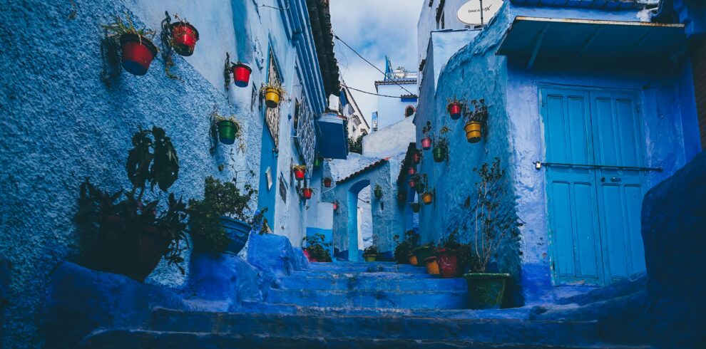 Colorful pots line the blue-washed walls of a narrow alley in Chefchaouen, Morocco.